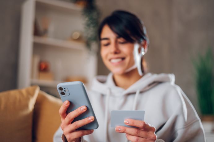 Femme souriante payant une facture avec carte bancaire sur smartphone